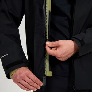 Person adjusting a zipper on a black jacket with a visible brand logo.