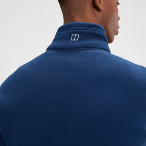 Person wearing a blue jacket with a logo on the collar against a light gray background
