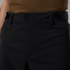 Close-up of black pants with a brown top worn by a person.