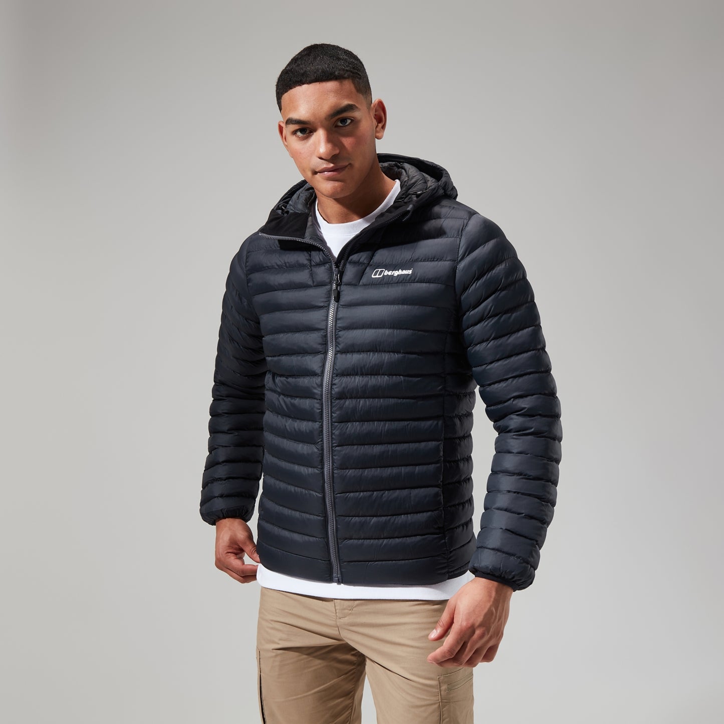 Man wearing a black puffer jacket with a brand logo on a gray background