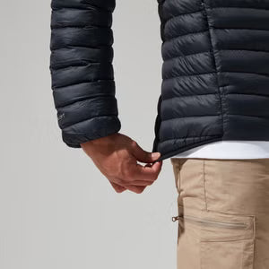 Person wearing a black puffer jacket and beige pants on a light gray background