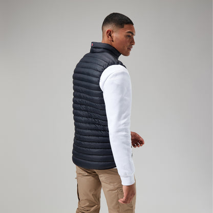 Man wearing a black puffer vest over a white long-sleeve shirt on a gray background