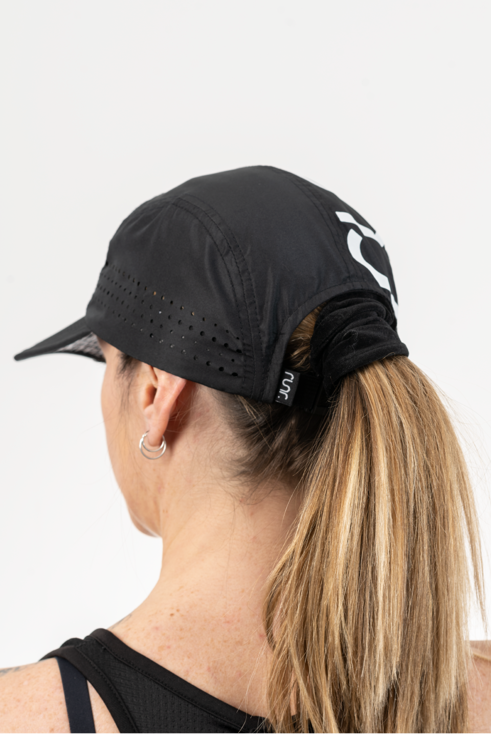 Black running cap worn in profile with RUNR logo and perforated crown panel.