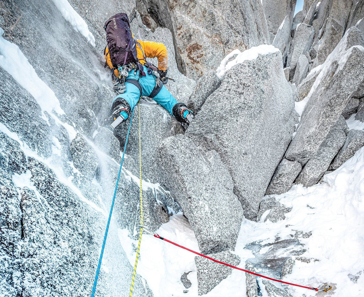 Climbing rope system with runner sling and carabiner on snowy rock