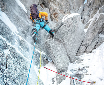 Climbing rope system with runner sling and carabiner on snowy rock