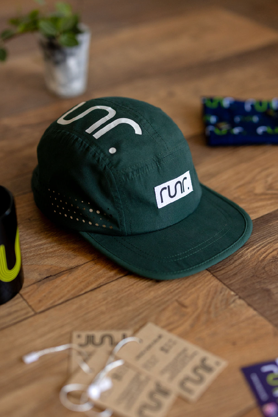 Dark green running cap with white logo patch and perforated side ventilation holes