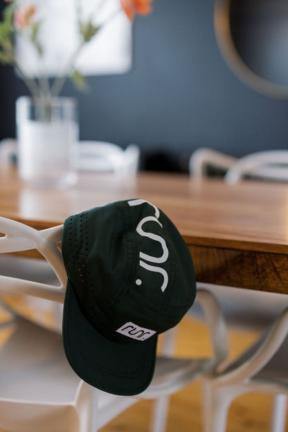 Dark green running cap with white logo patch and side ventilation perforations