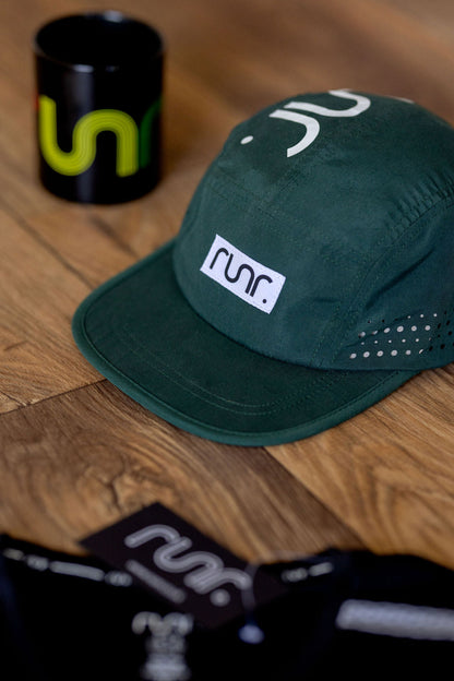Dark green cap with white square logo patch and perforated side panels