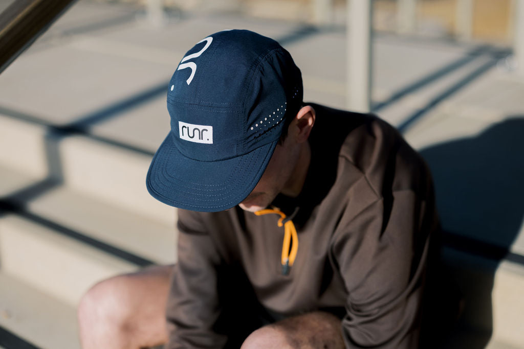 Navy running cap worn on head with white runr logo and curved brim