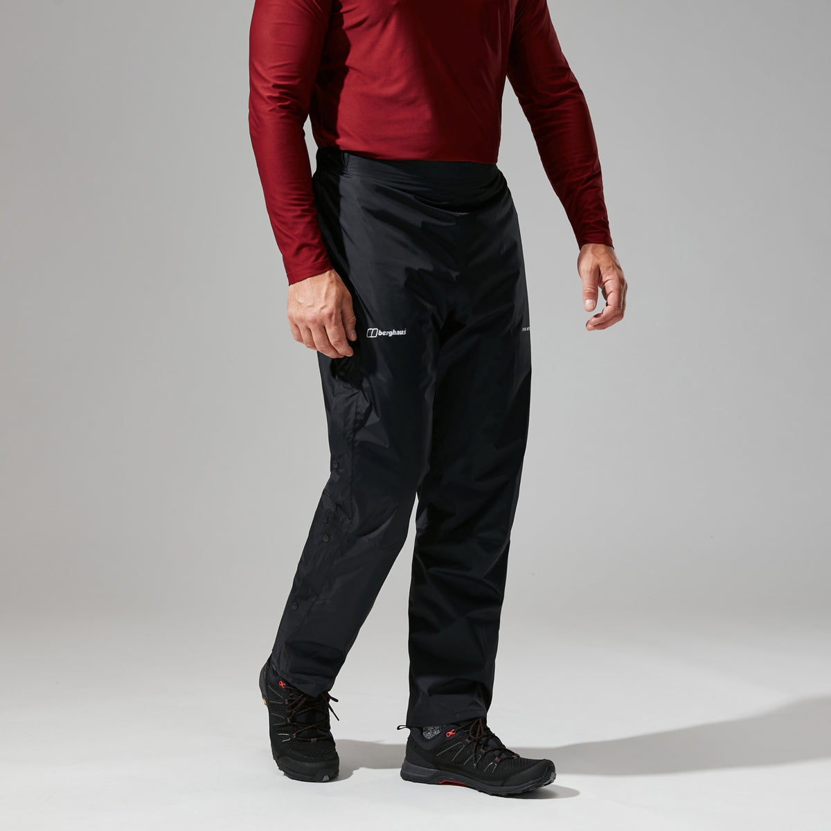 Black waterproof overtrousers on model, side view with elastic cuff hem