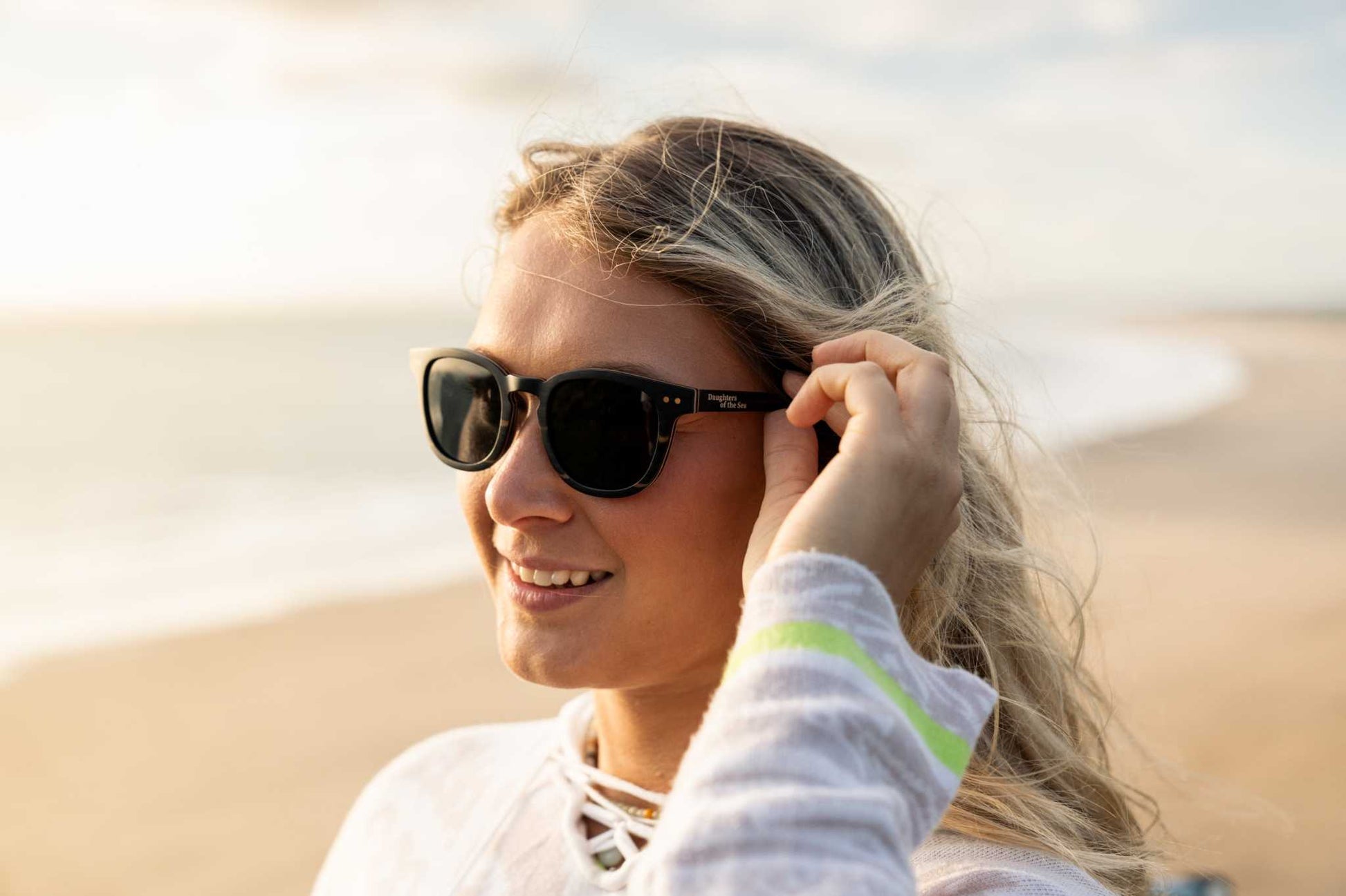 Person wearing black sunglasses with a surfboard edge visible