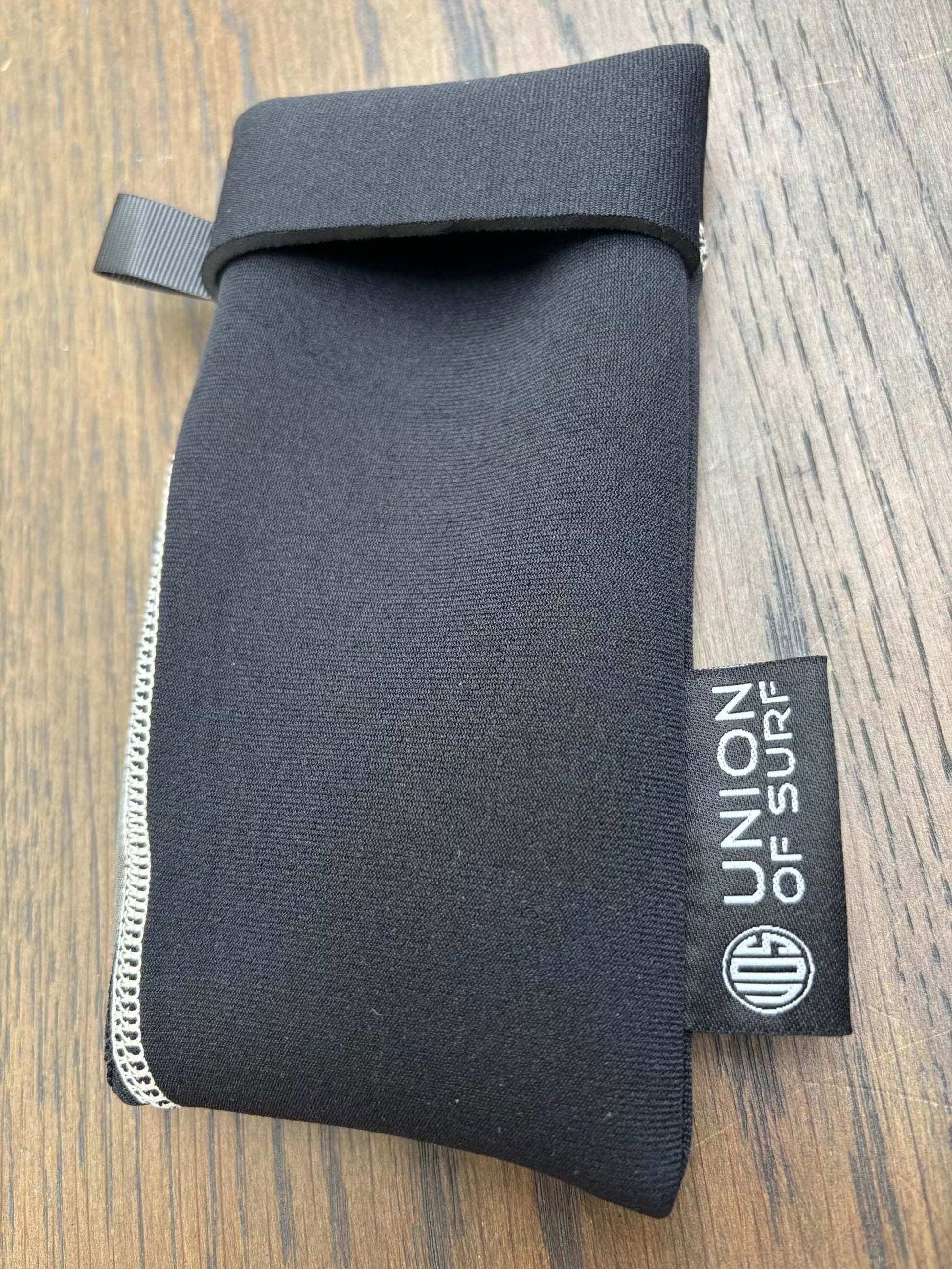 Dark gray sunglasses case with black strap and small black side label