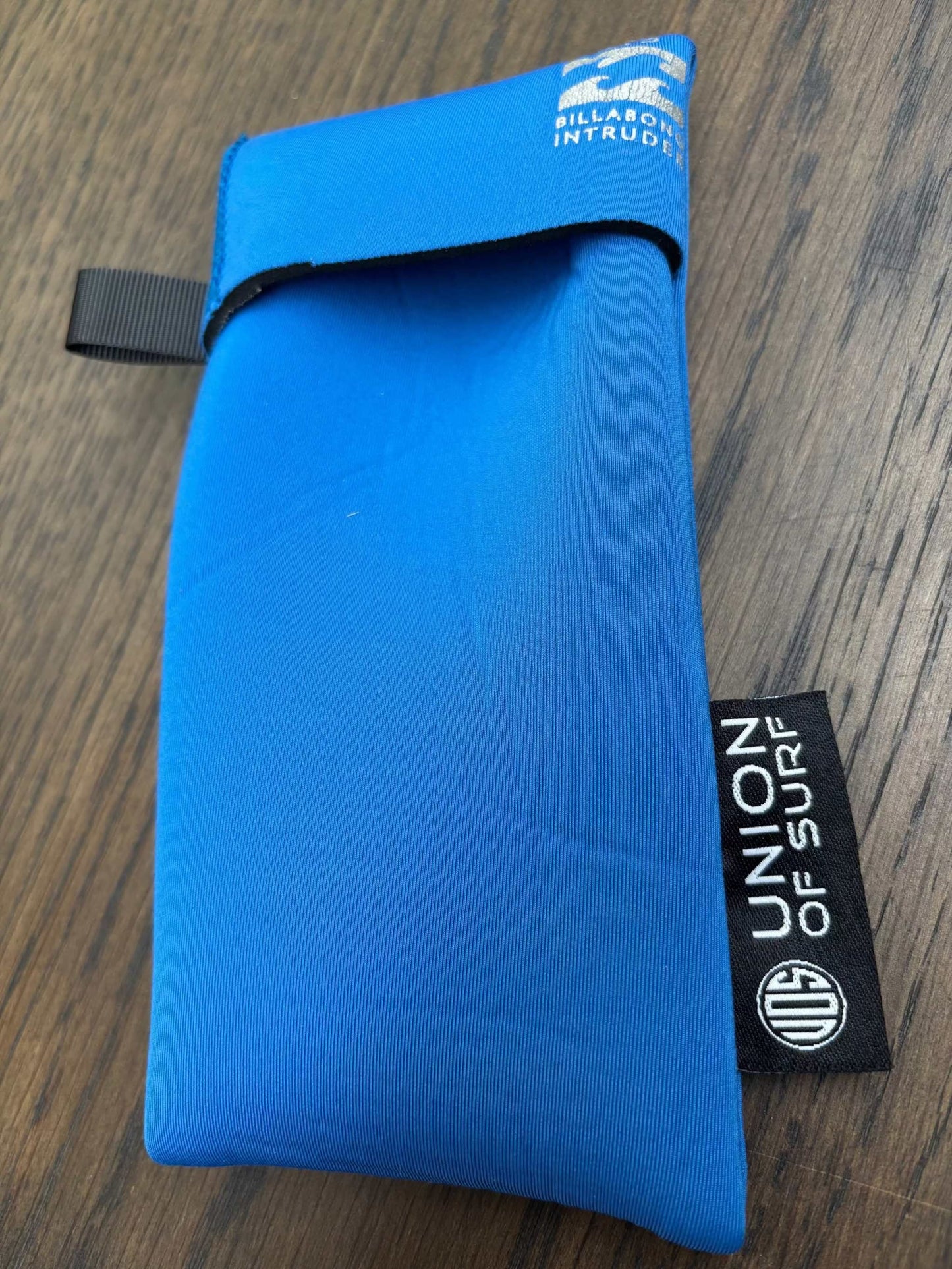 Blue sunglasses case with black carrying strap and small black side label