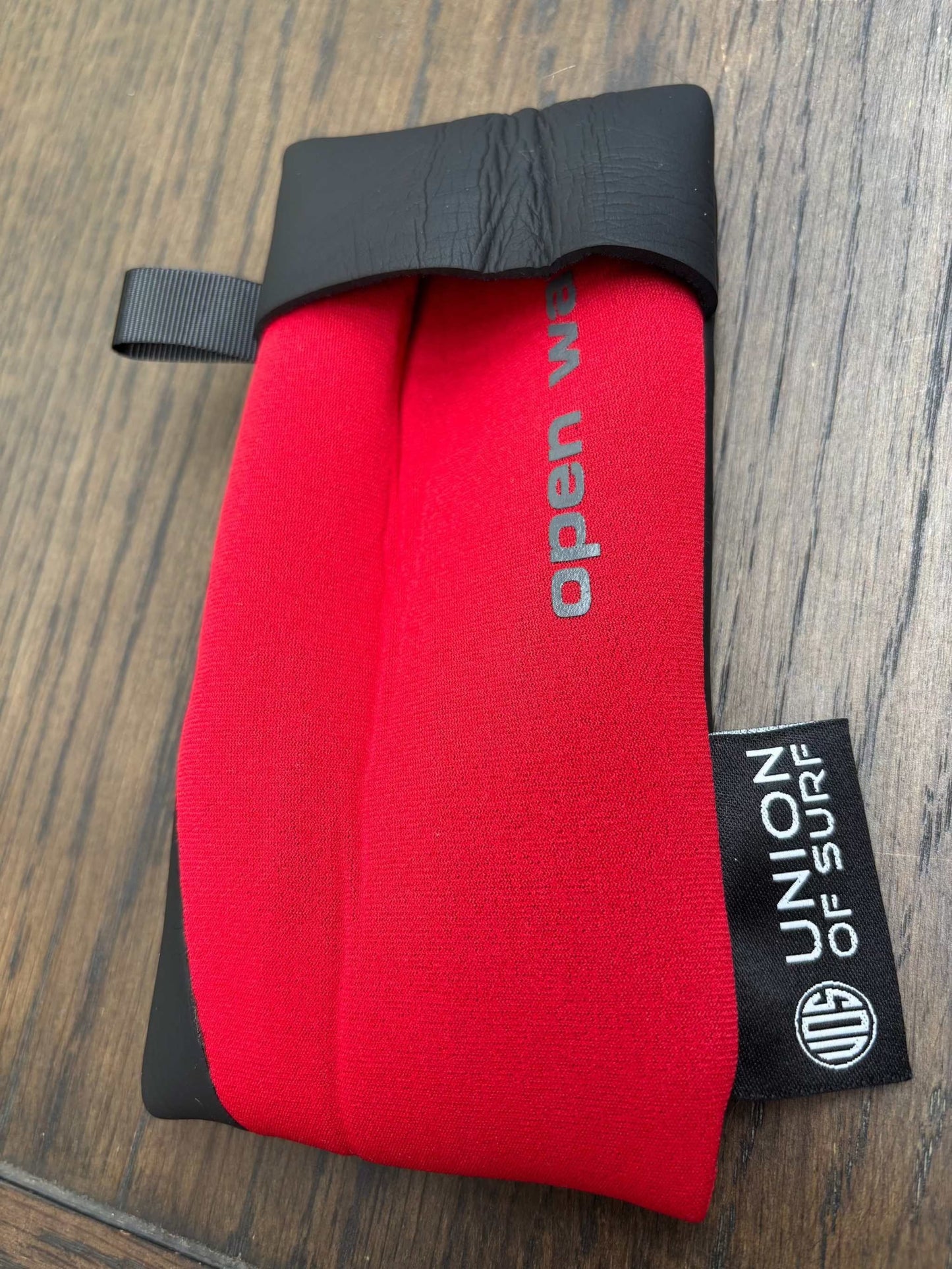 Red sunglasses case with black carrying strap and small black side label