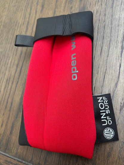 Red sunglasses case with black carrying strap and small black side label