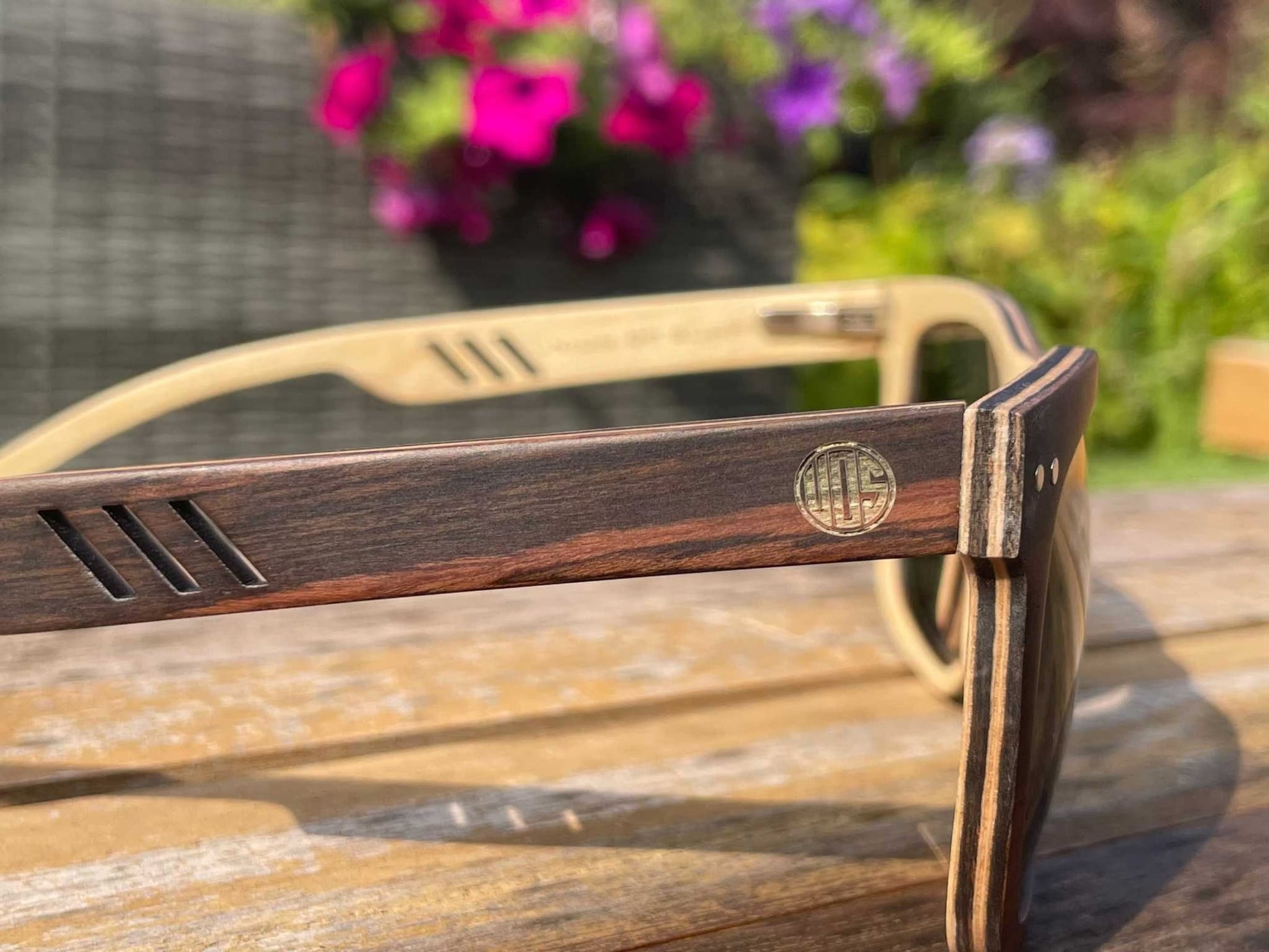 Sunglasses temple close-up with circular logo on dark brown frame