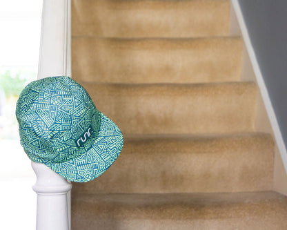 Green-and-teal geometric running hat resting on a white railing