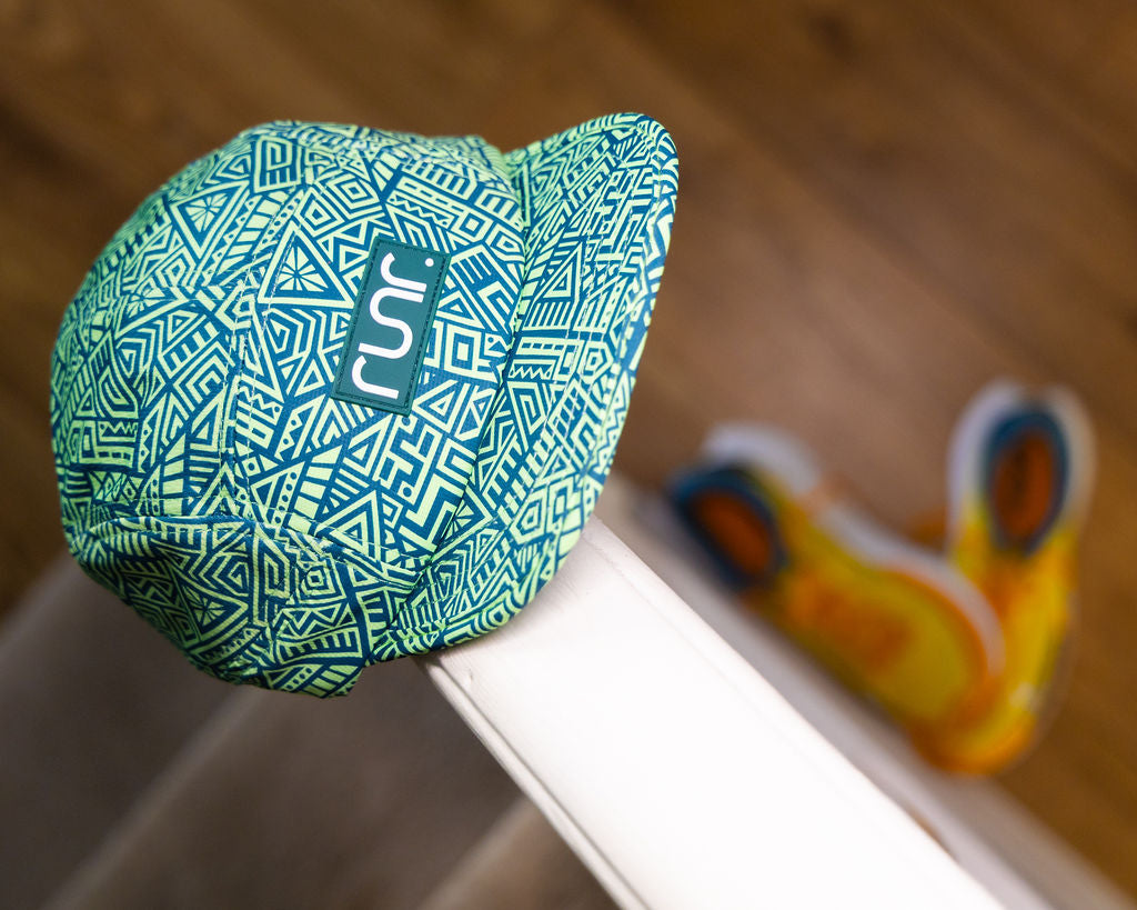 Green-and-teal geometric running hat with runr logo panel, side view