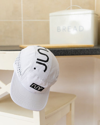White running hat angled view with black "C" logo and perforated side holes