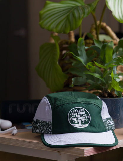 Green technical running hat with white brim and leave-nothing foot-print patch logo.