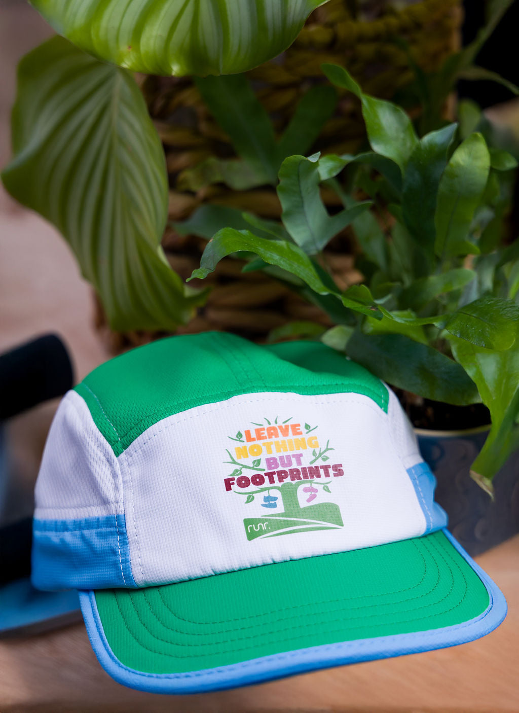 Technical running hat front logo in green, white, and blue with curved brim