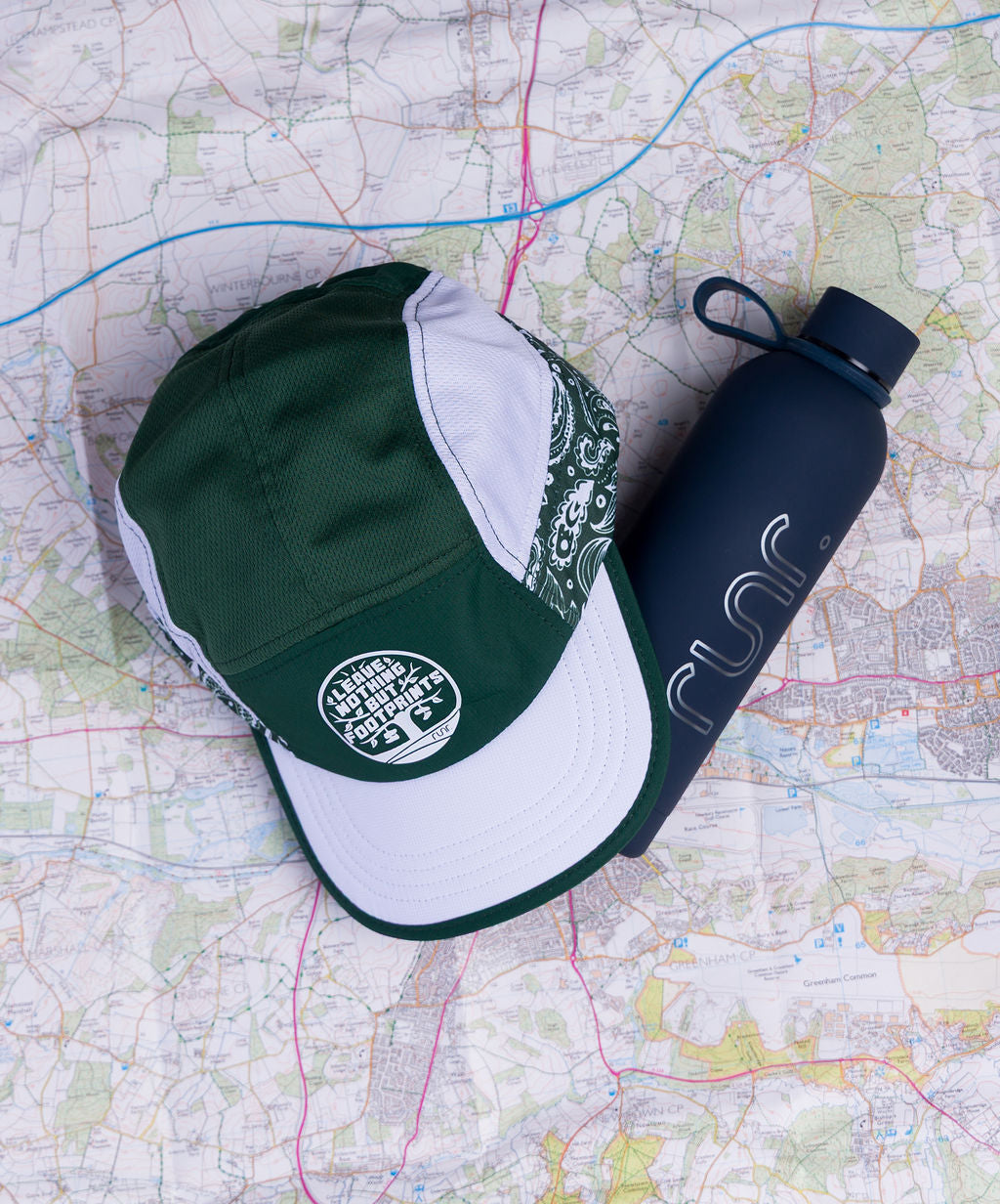 Technical running hat with green crown, white brim, and side graphic logo patch