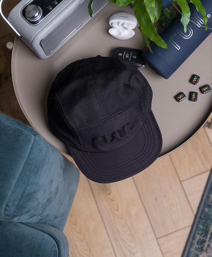 Black running cap on table with r un. logo front and curved brim