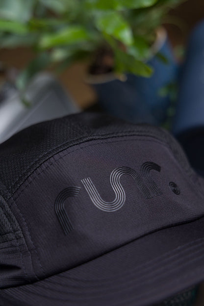 Black running cap front panel close-up with r un. logo embroidered