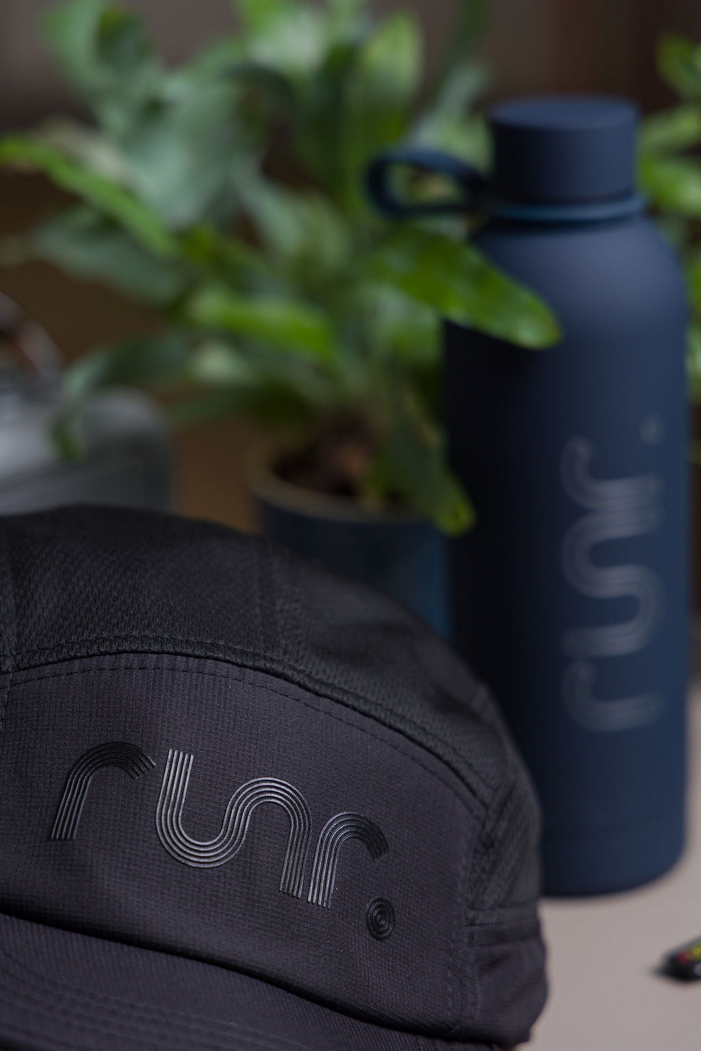 Black running cap side and front close-up with r un. logo and textured fabric