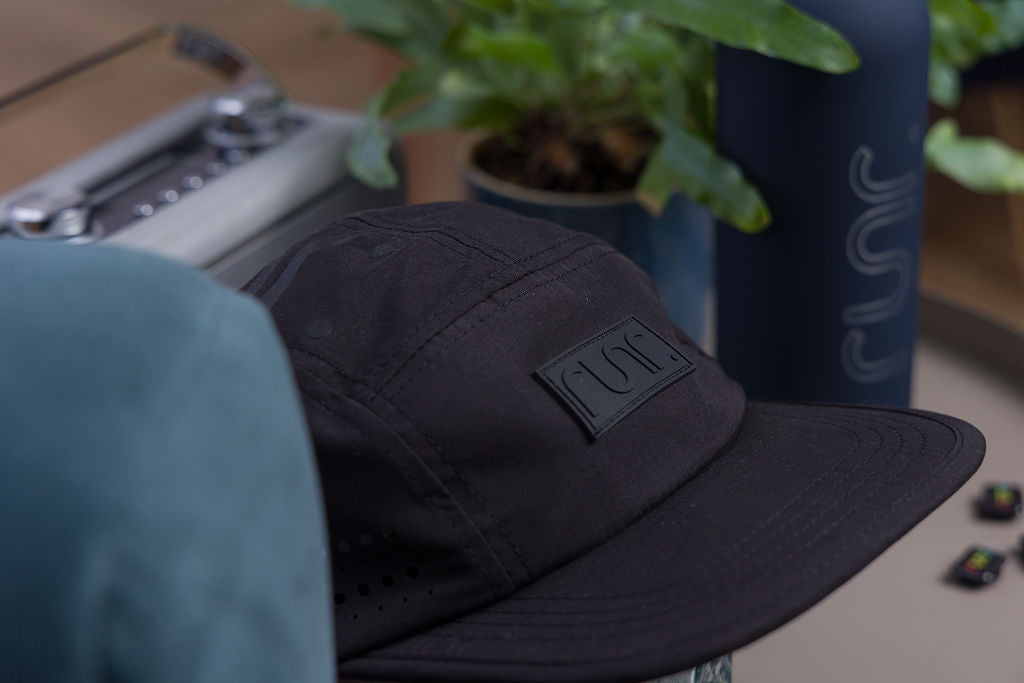 Black technical running cap with curved brim and Runr logo patch on the side.