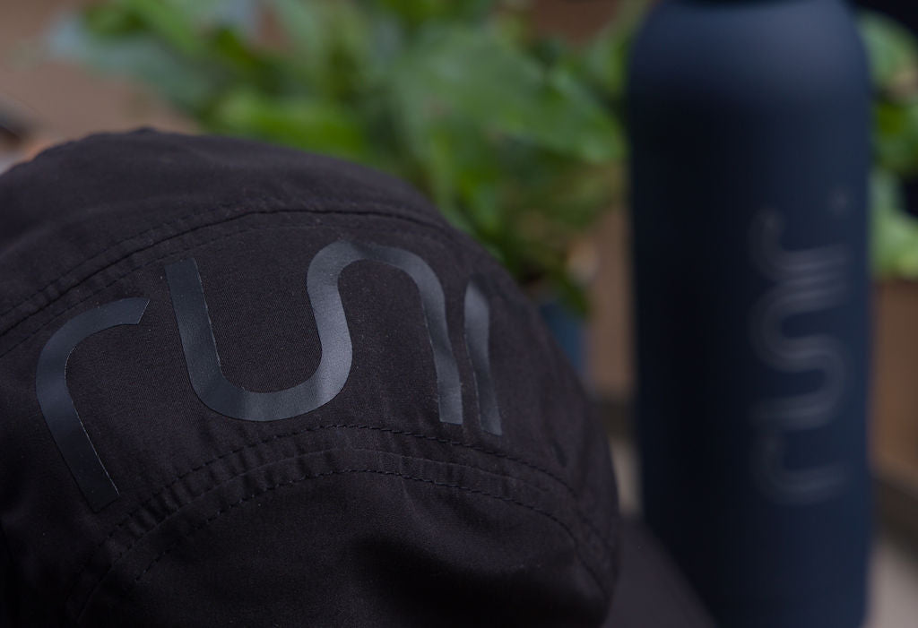 Black technical running hat with large rear graphic and stitched seams.