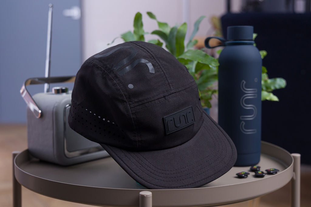 Black technical running cap with curved brim and Runr logo patch at the side.