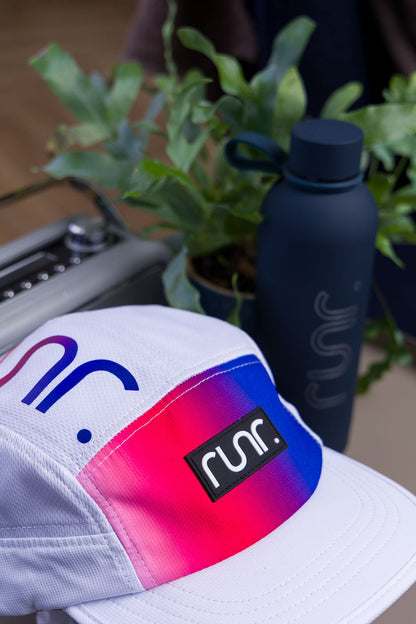 White technical running cap with rainbow gradient patch and runr logo badge