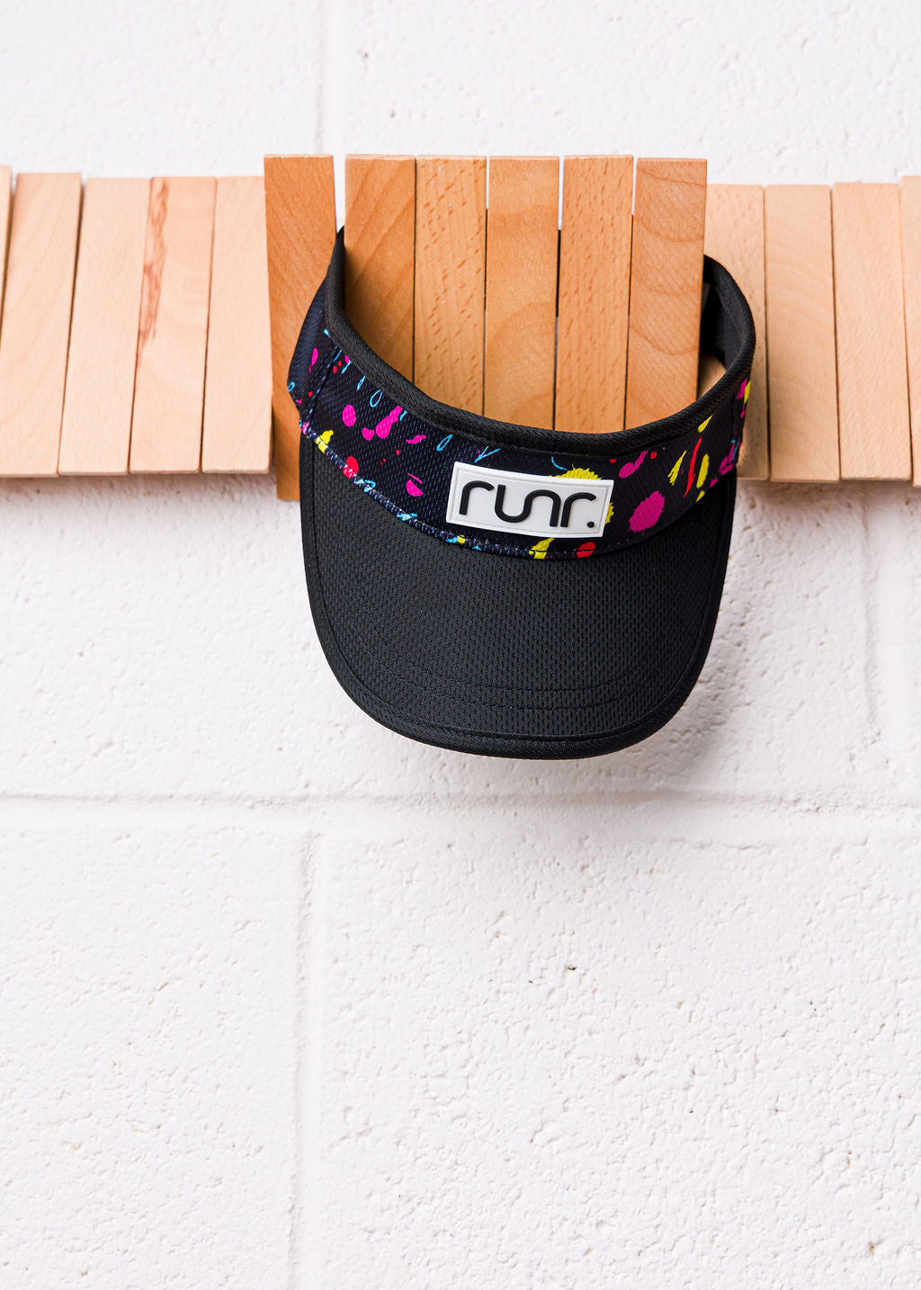 Black visor with multicolor splatter front band and 'runr' logo, side view