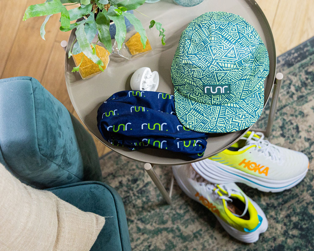 Geo-pattern technical running hat on a chair arm, teal and green with logo