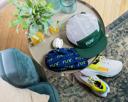 Teal and white running hat on a table with shoes, bag, and water bottle
