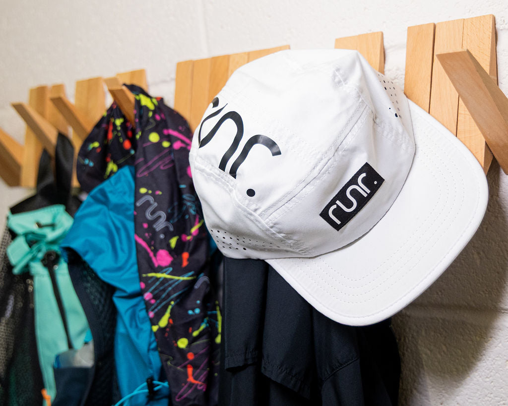 White running cap with black logo, worn with other colorful clothing on display