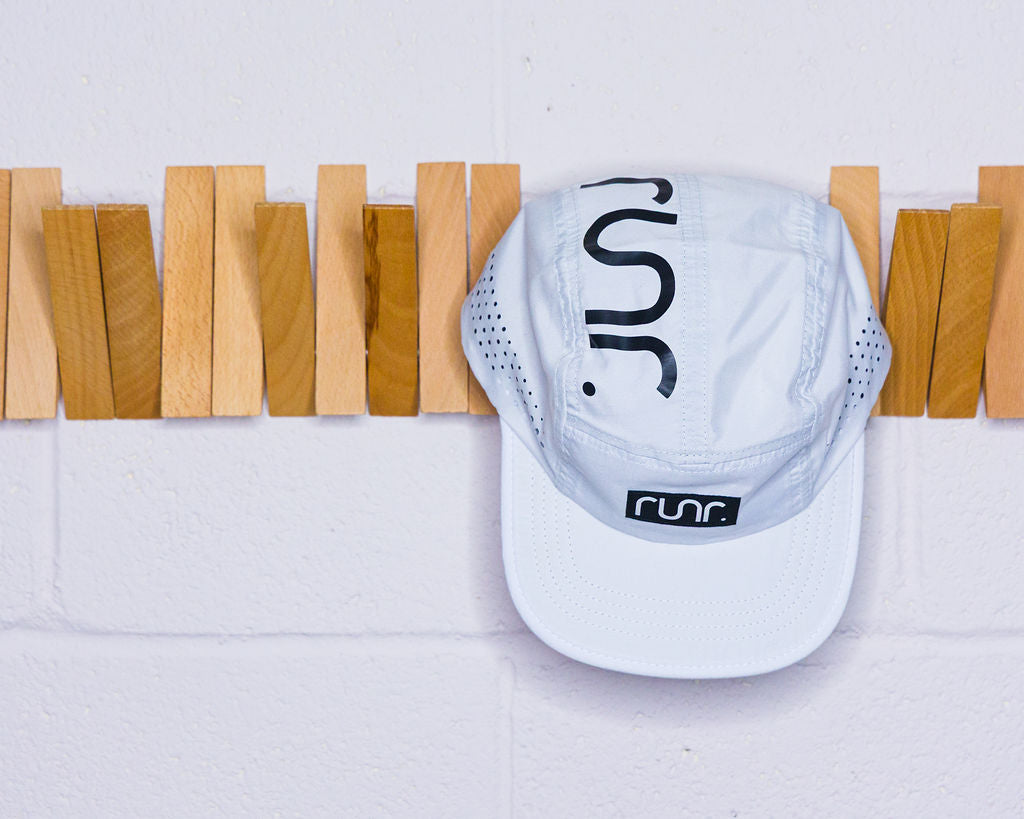 White technical running hat with black "C" back logo and adjustable front strap