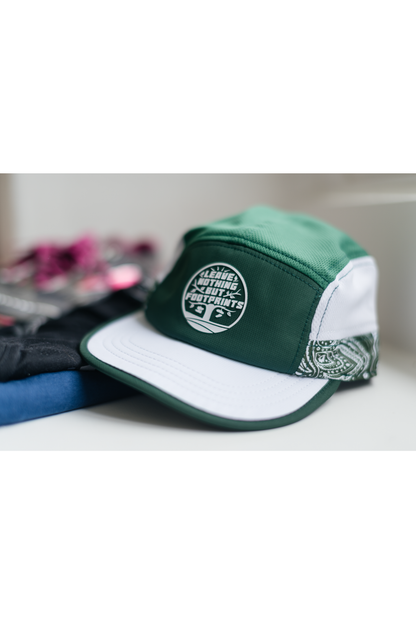 Green and white running cap with leave-nothing foot-print patch and adjustable strap.