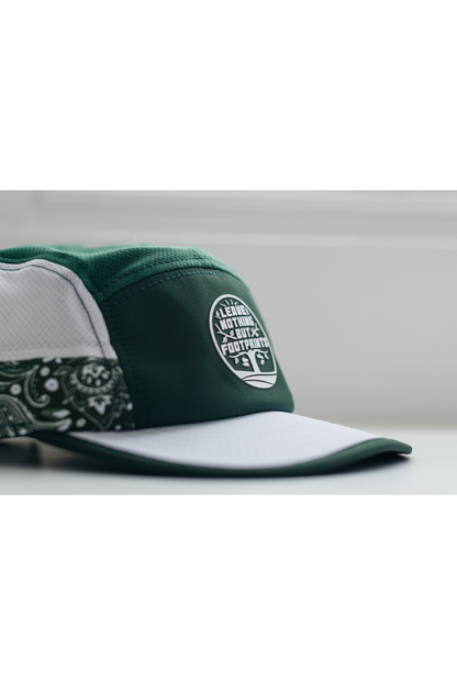 Side view of green running hat with white brim edge and leave-nothing patch logo.