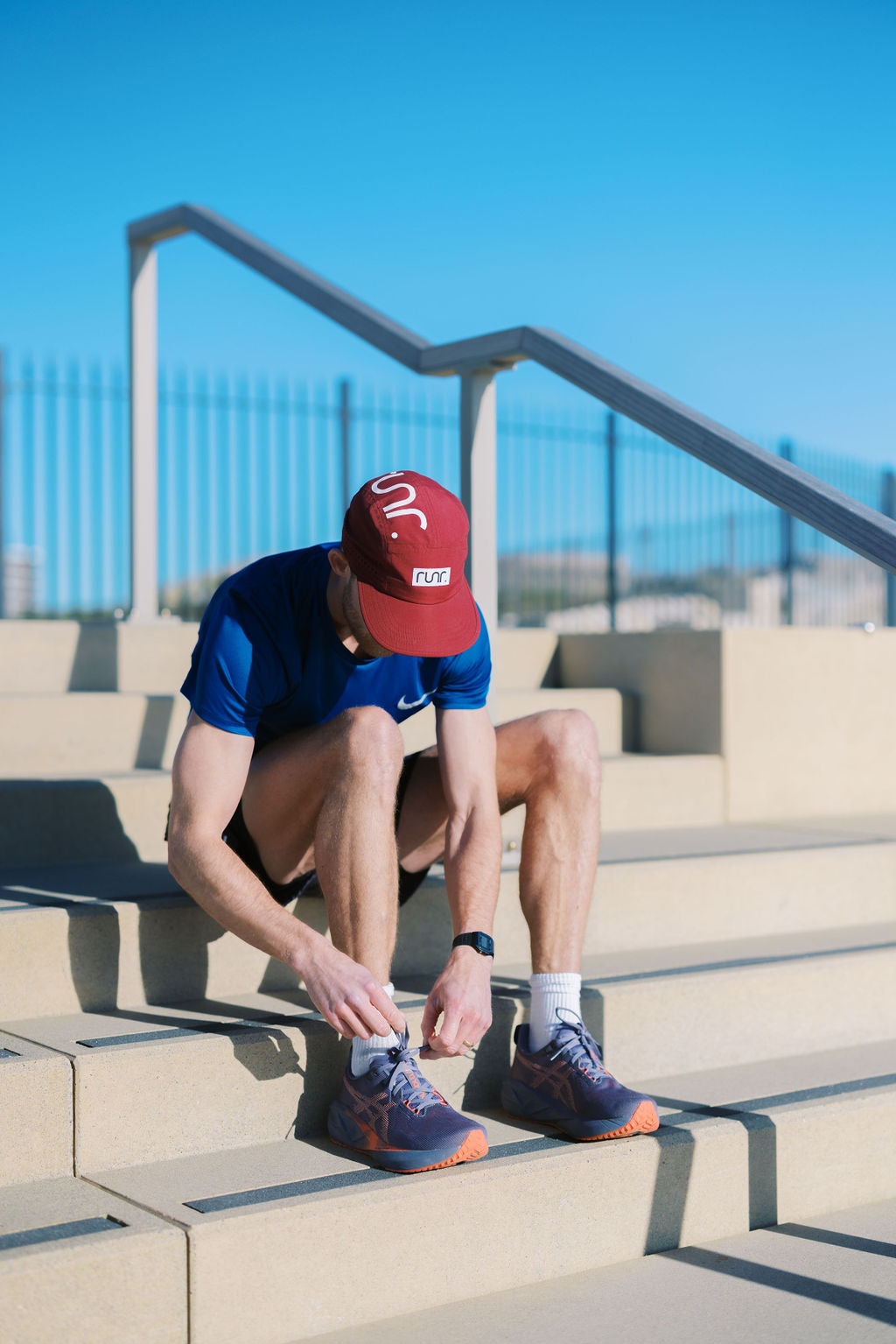 Red running hat with white RUNR logo, worn by person