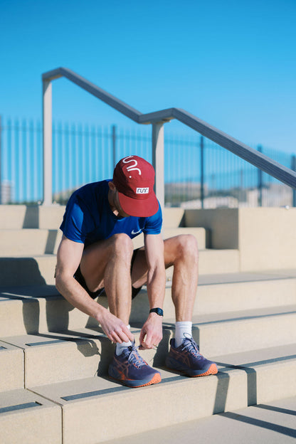 Red running hat with white RUNR logo, worn by person