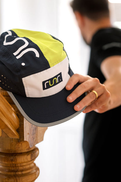 Technical running hat close-up, navy crown with lime insert and white logo patch