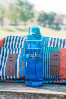 Nalgene 700ml blue water bottle with blue lock-top cap, standing on a cushion