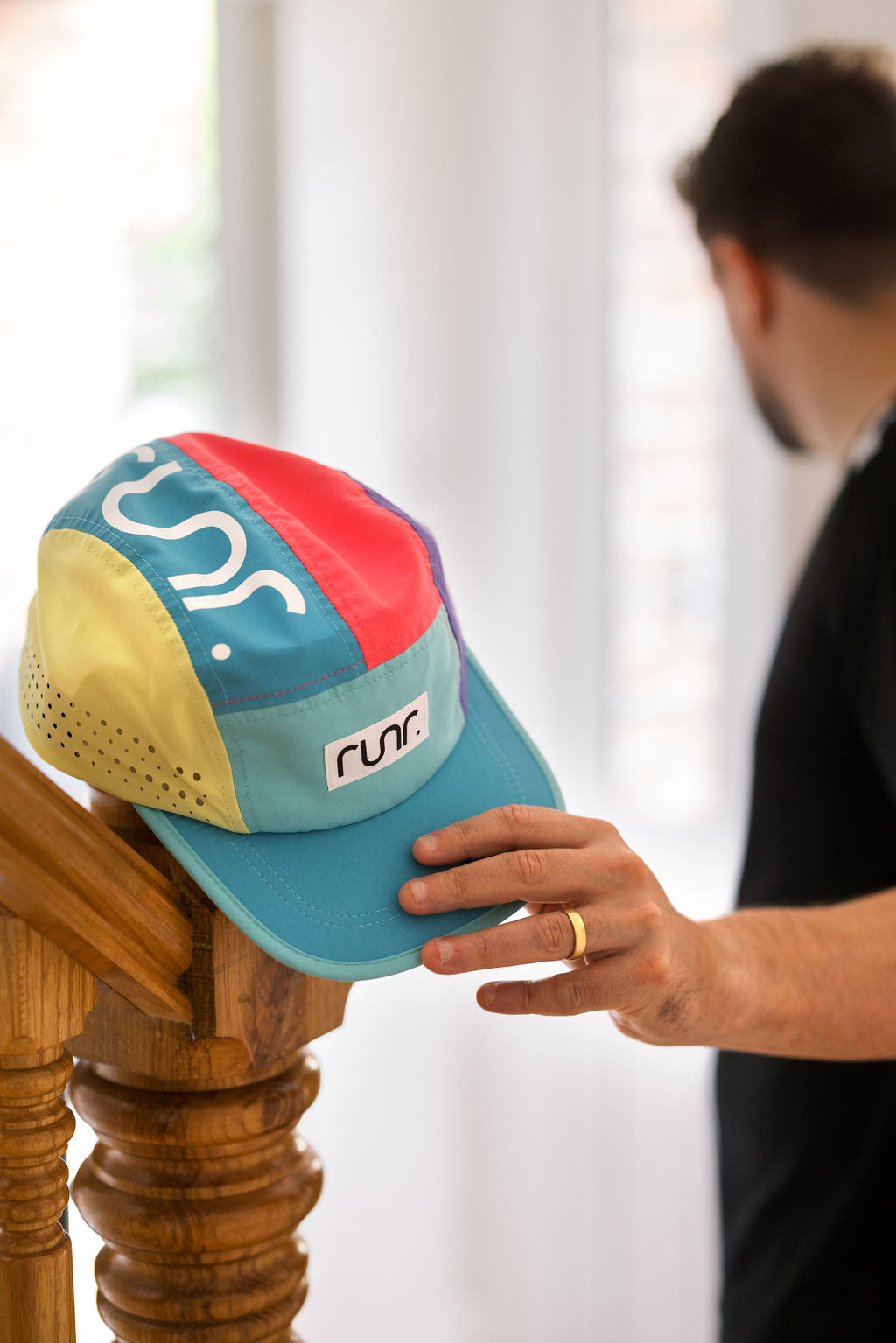 Multicolor running hat with side graphic, teal brim, and yellow perforated panel.