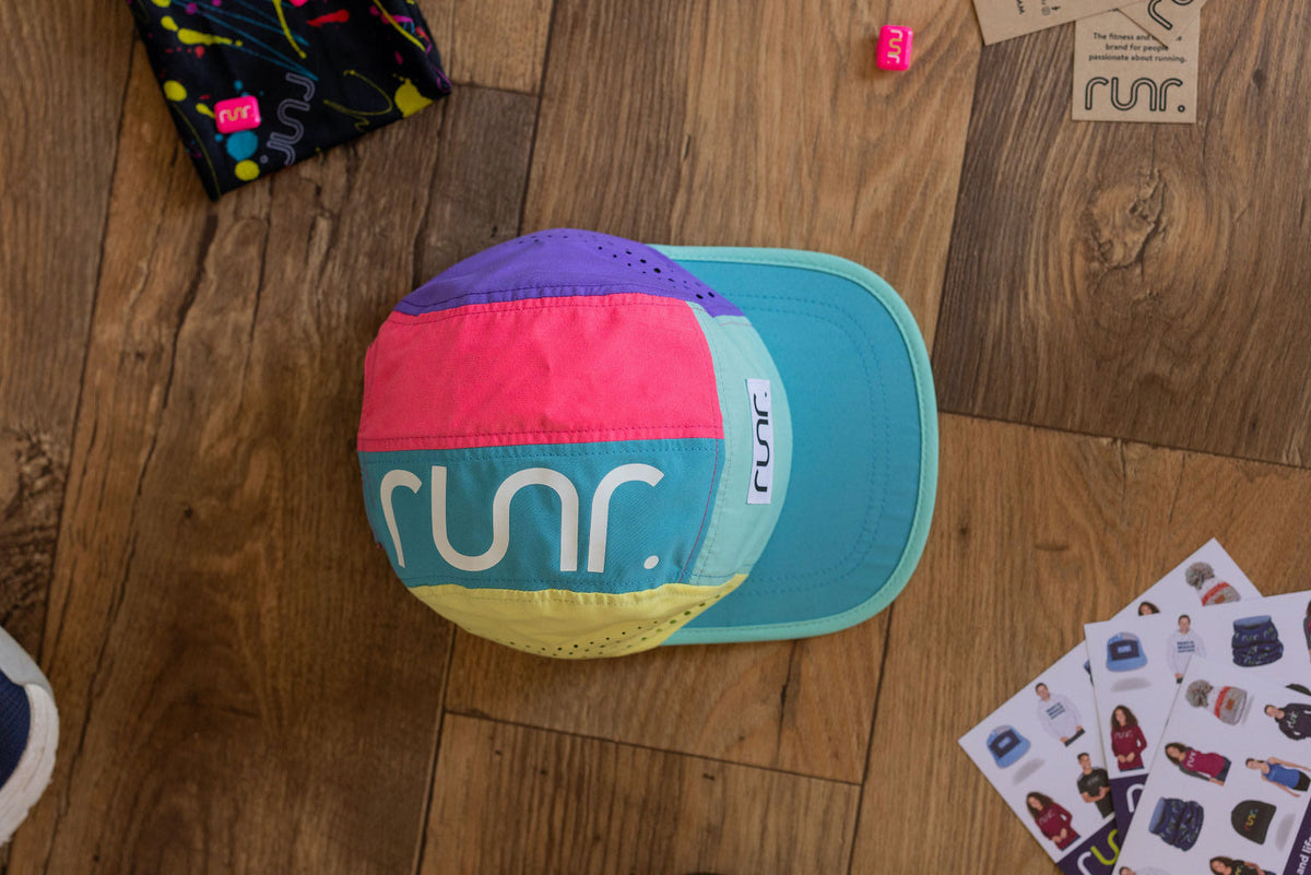 Multicolor running hat lying flat with front logo patch and teal blue brim.