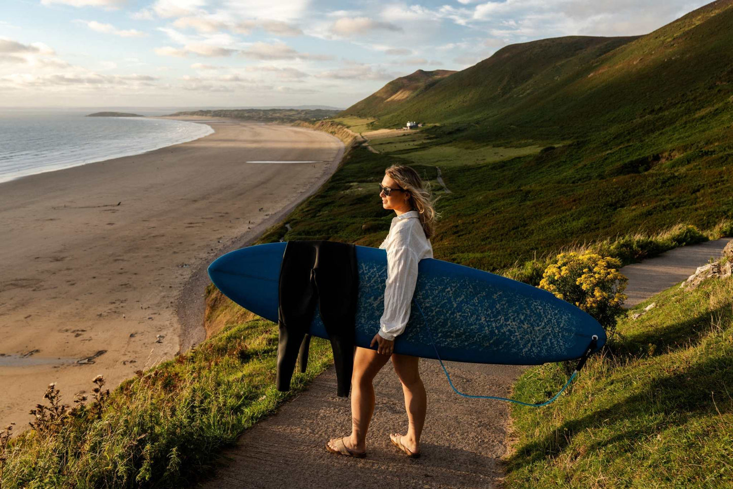 Blue and black surfboard leaning upright near a sandy shoreline