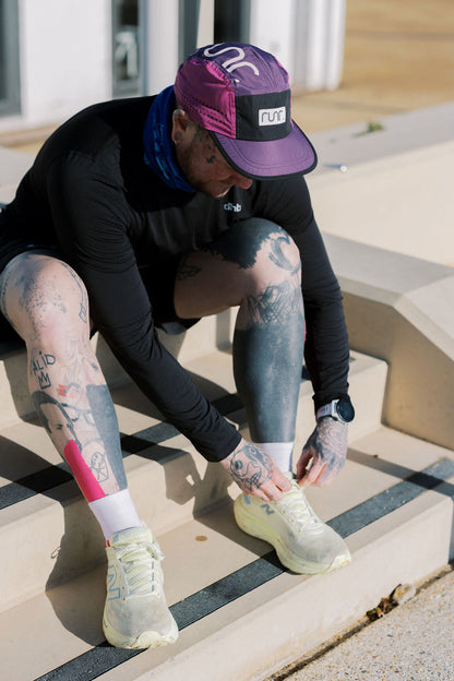 Runner wearing purple and black technical cap with white logo patch