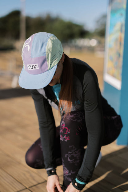 Technical running hat on model, light blue brim with purple and mint color-block panels