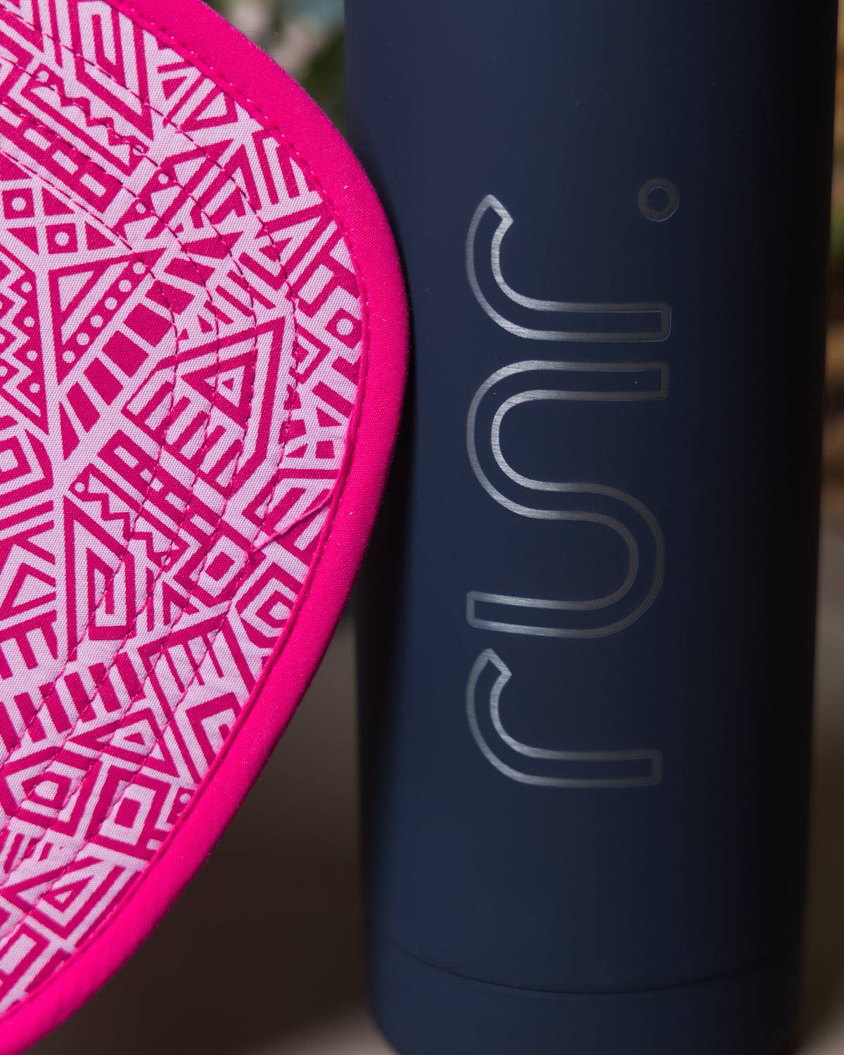 Pink technical running hat brim close-up with geometric pattern and black trim.